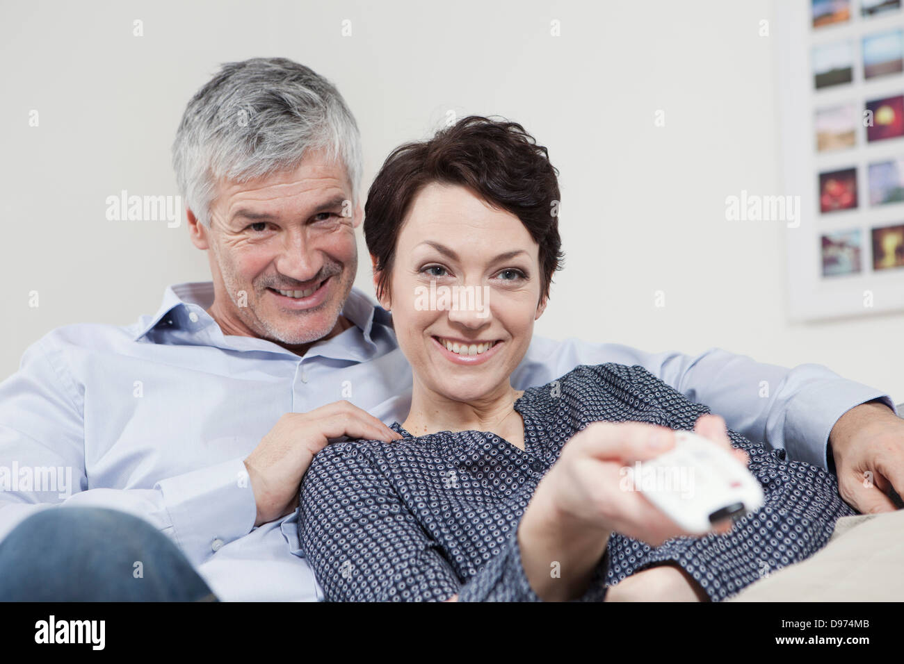 Germany, Bavaria, Munich, Couple changing channels with remote control, smiling Stock Photo