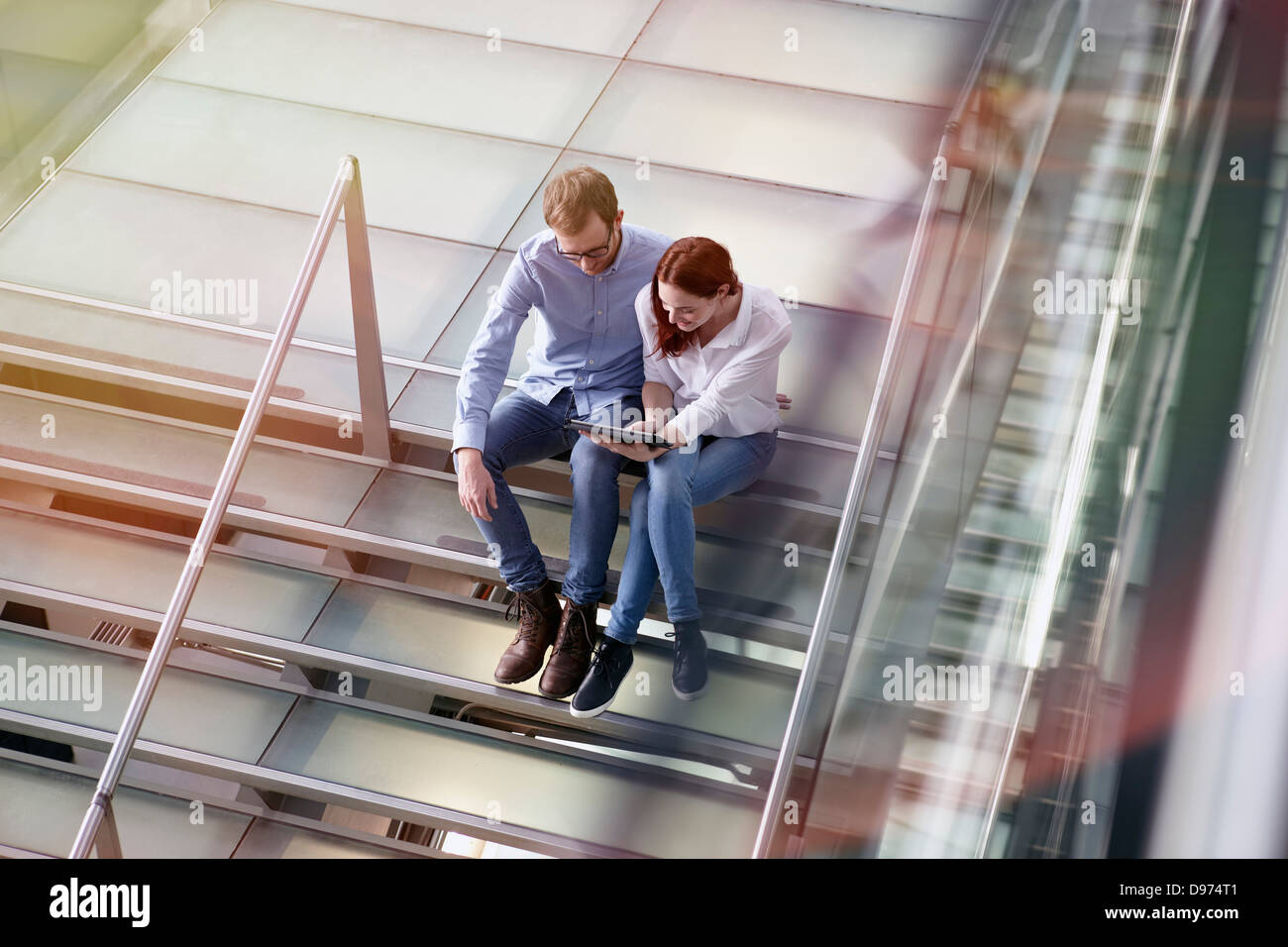 Germany, Cologne, Young woman and mid adult man with tablet at stairs Stock Photo