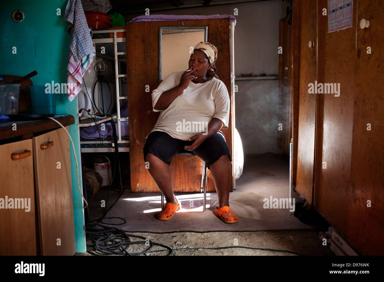 <p>Jeremine smokes cigarette in one-bedroom corrugated iron house in Blikkiesdorp in Delft Cape Town South Africa family were Stock Photo