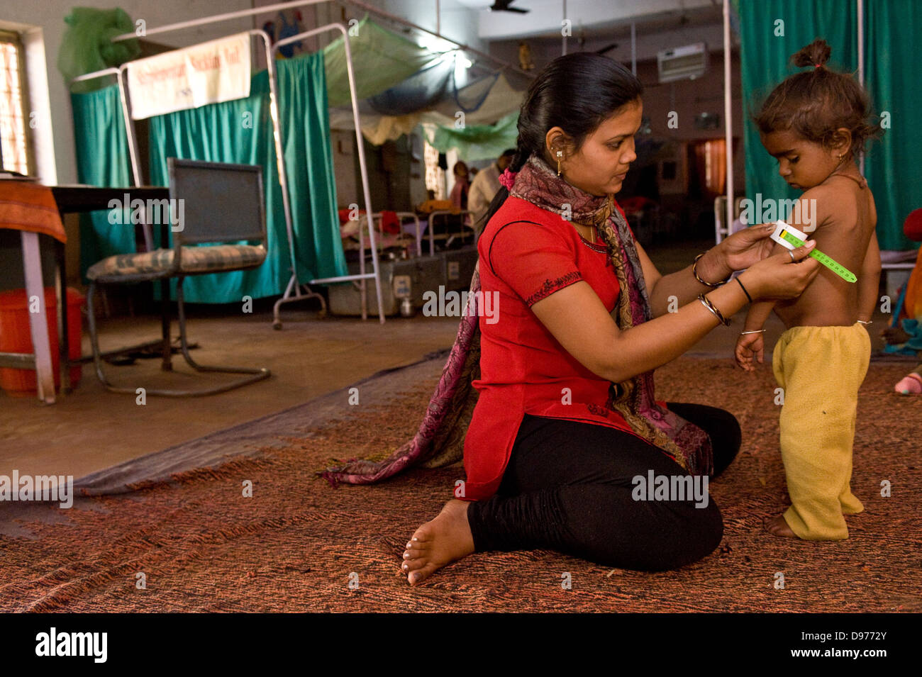 The health worker is checking the upper arm circumference of this young child in India with a rapid test – to ensure that she is Stock Photo