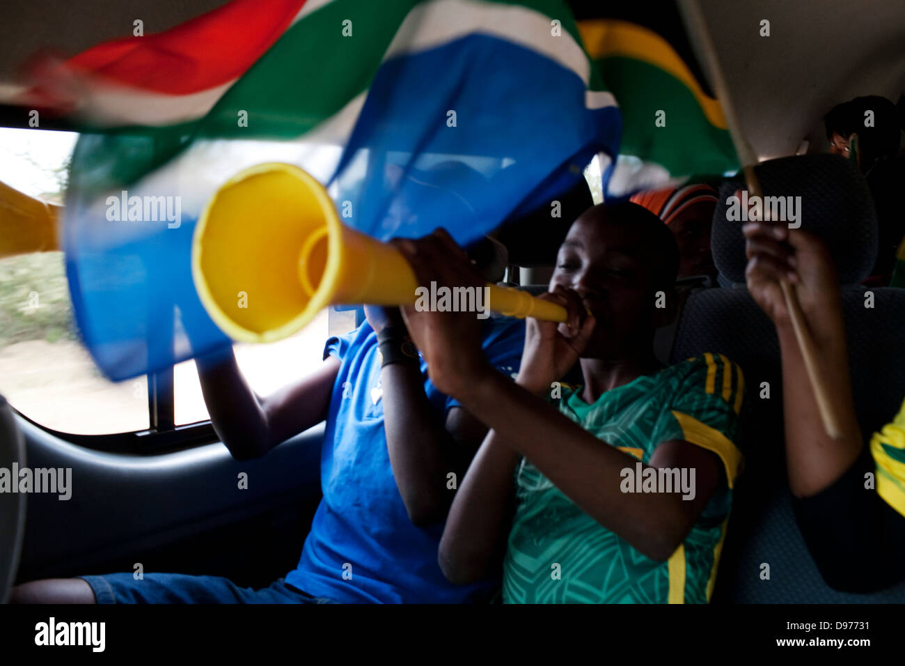 Football fans blow vuvuzelas wave South African flag in taxi They on way to fan park viewing site to watch on large television Stock Photo