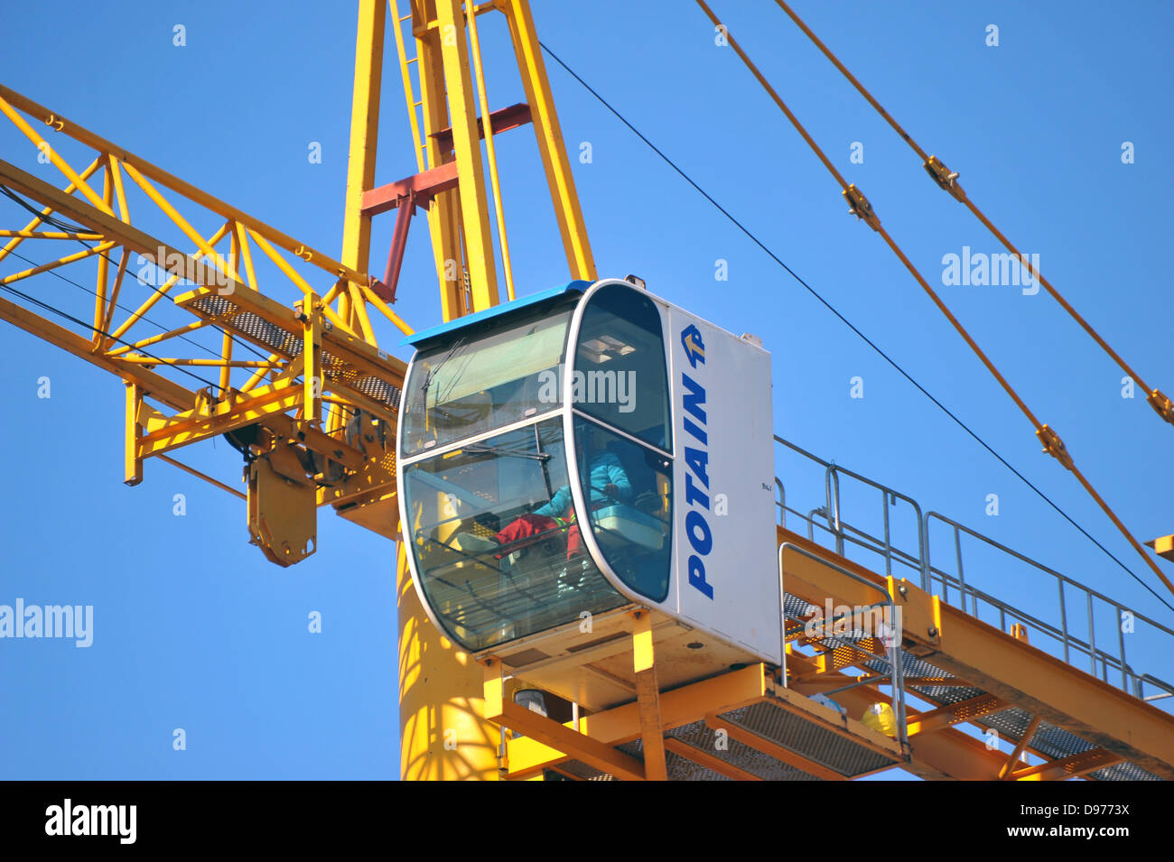 A crane operator sits in the glass cab of a tower crane above Johannesburg. Stock Photo