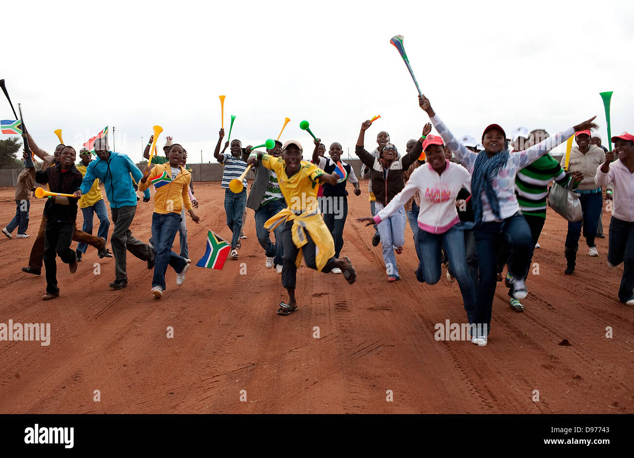Football fans dance blow vuvuzela wave South African flag park viewing