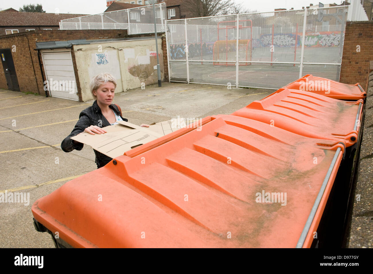 An attractive trendy young woman recycling cardboard boxes in Broadway