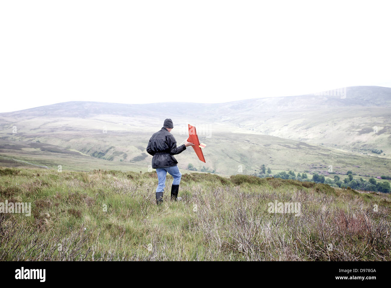 A man with a remote control airplane in walking in mountainous landscape Stock Photo