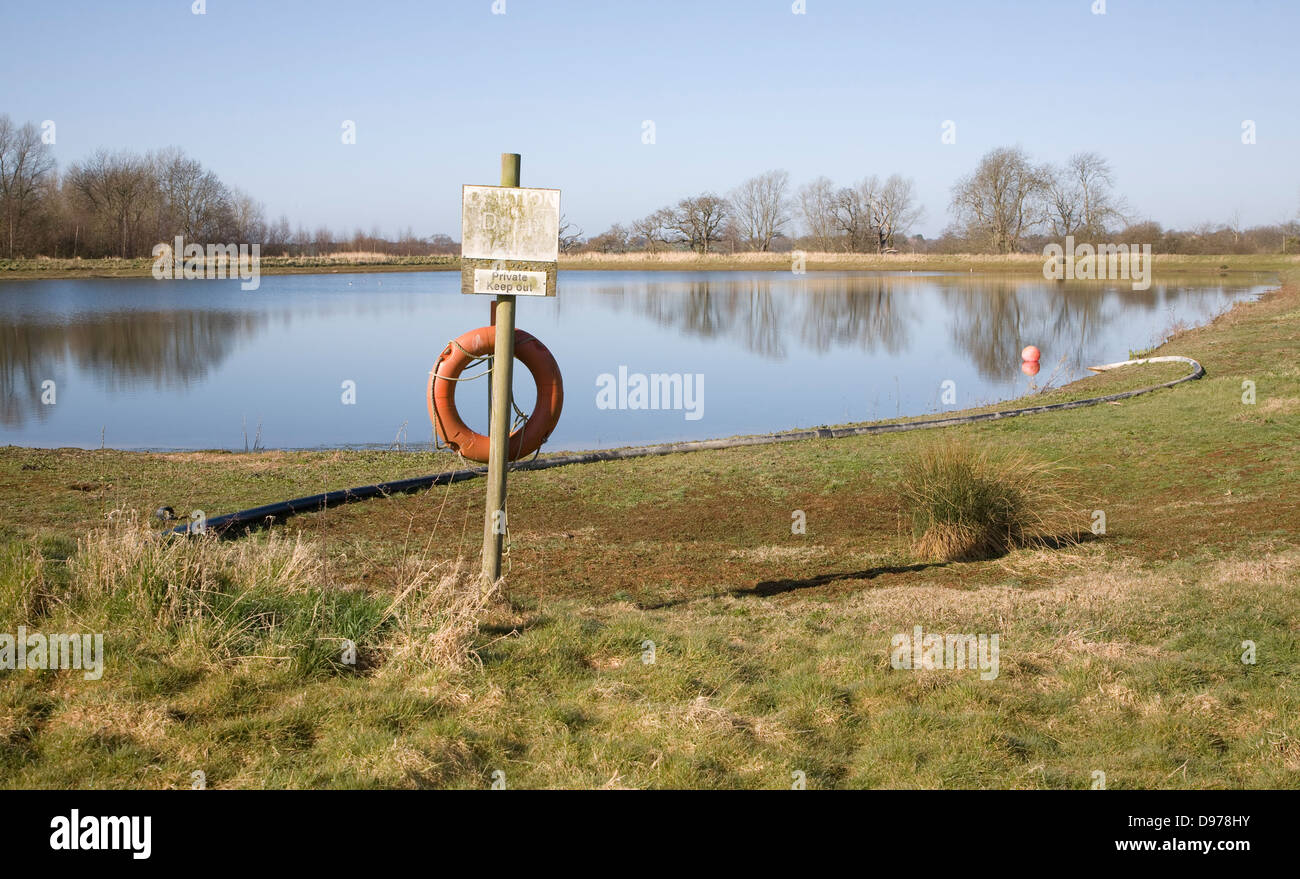 Orange life saving ring by irrigation water reservoir, Sutton, Suffolk, England Stock Photo