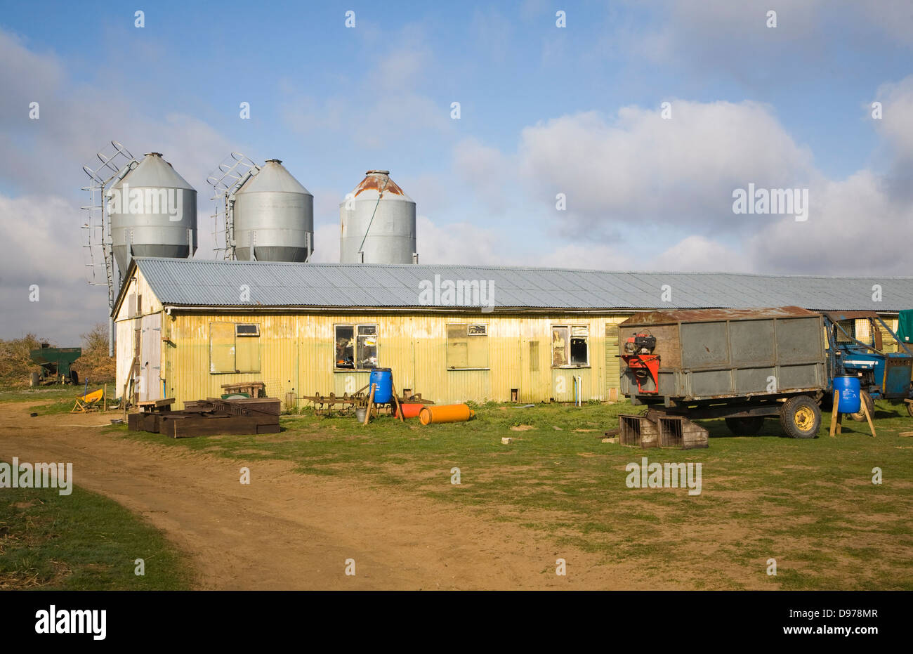 To be captioned after editing Three metal feed storage silos and barn in farmyard, Alderton, Suffolk, England Stock Photo
