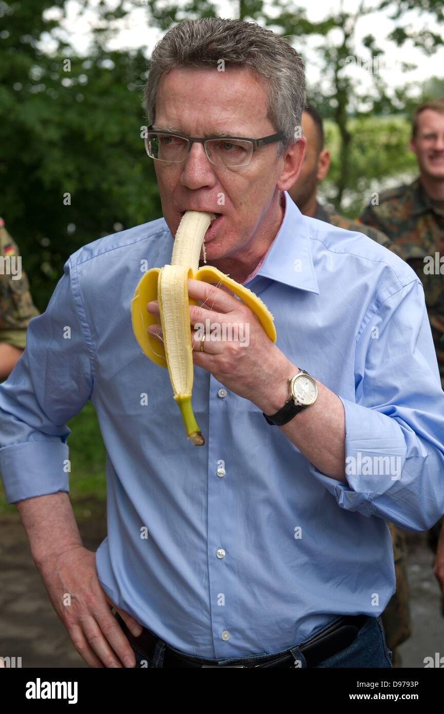 Penkefitz, Germany. 13th June, 2013. German Defence Minister Thomas de Maiziere visits soldiers of the Bundeswehr ánd eats a banana at a dike near Penkefitz, Germany, 13 June 2013. Soldiers of the logistics battalion 141 from Neustadt am Ruebenberge reinforced dikes with sandbags in the area Luechow-Dannenberg. Photo: Sebastian Kahnert/dpa/Alamy Live News Stock Photo