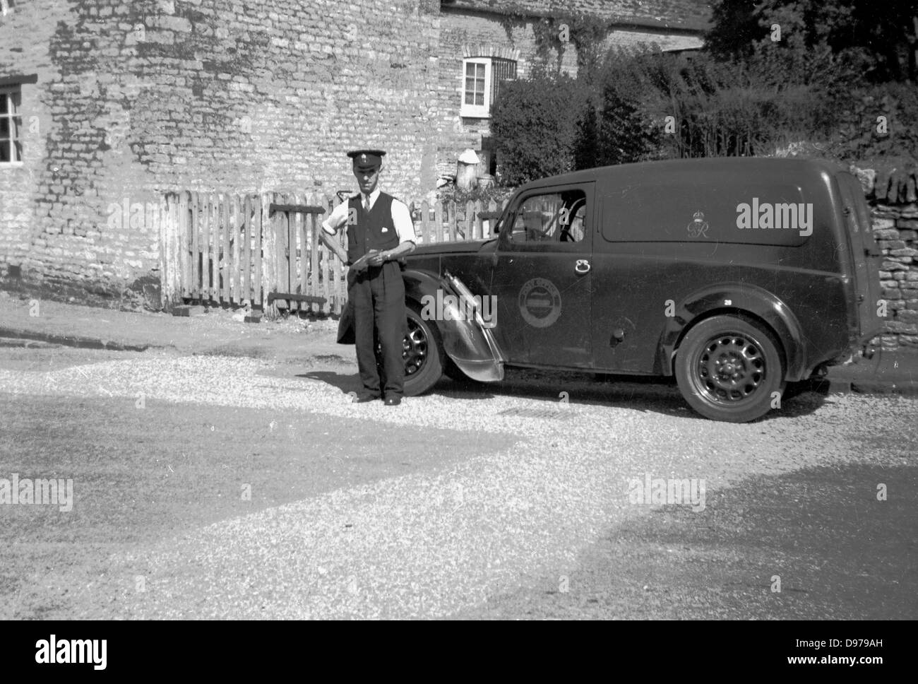 Historical 1950s. Rural England and a British Royal Mail postman stands proudly by his delivery van. Stock Photo