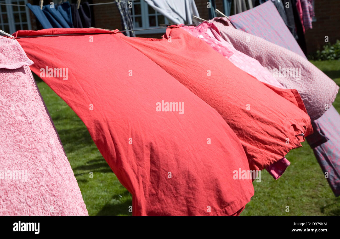 Red pink and purple clothes drying on washing line Stock Photo