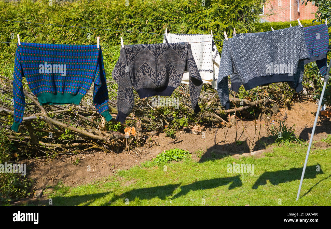 Woollen jumpers drying on a washing line in the sun, UK Stock Photo