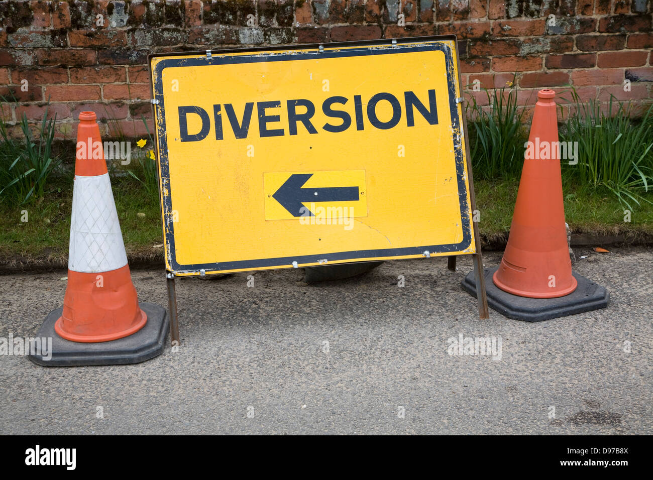 Yellow rectangular diversion sign with arrow pointing standing by two traffic cones, UK Stock Photo