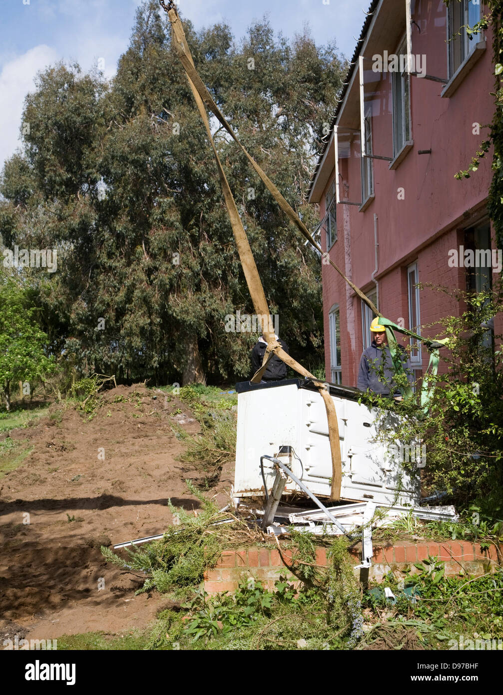 Crane and workmen removing Aga cooker from house about to be demolished