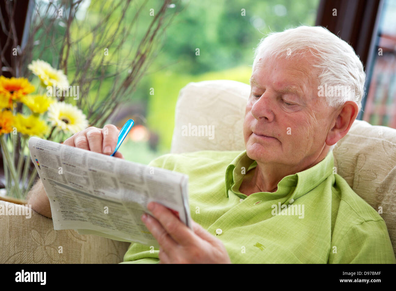 Seventies Man Active Retirement Lifestyle Reading Newspaper doing Crossword Stock Photo