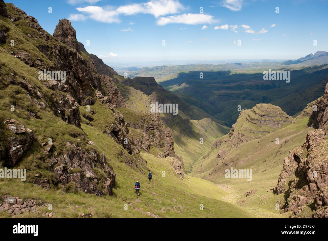 Hikers decending from the escarpment to Twins Cave, Ukhahlamba Drakensberg Park, South Africa Stock Photo