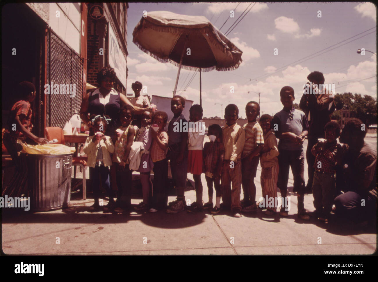 Ghetto Black Children Line Up For Snow Cones From A Sidewalk Vendor On Chicago's West Side In The Summer Of 1973, 06/1973 Stock Photo