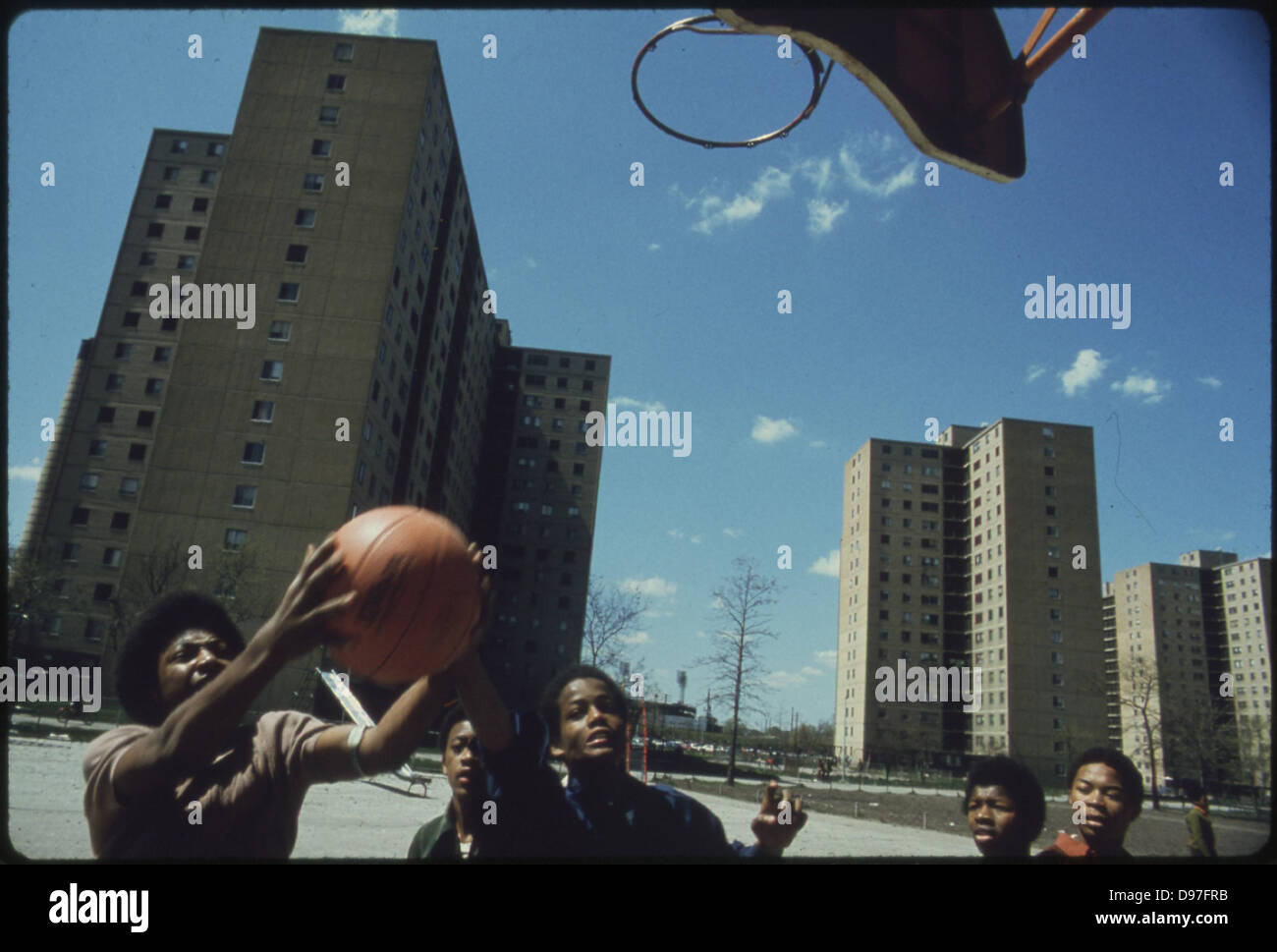 Black Youths Play Basketball At Stateway Gardens' Highrise Housing Project On Chicago's South Side, 05/1973 Stock Photo