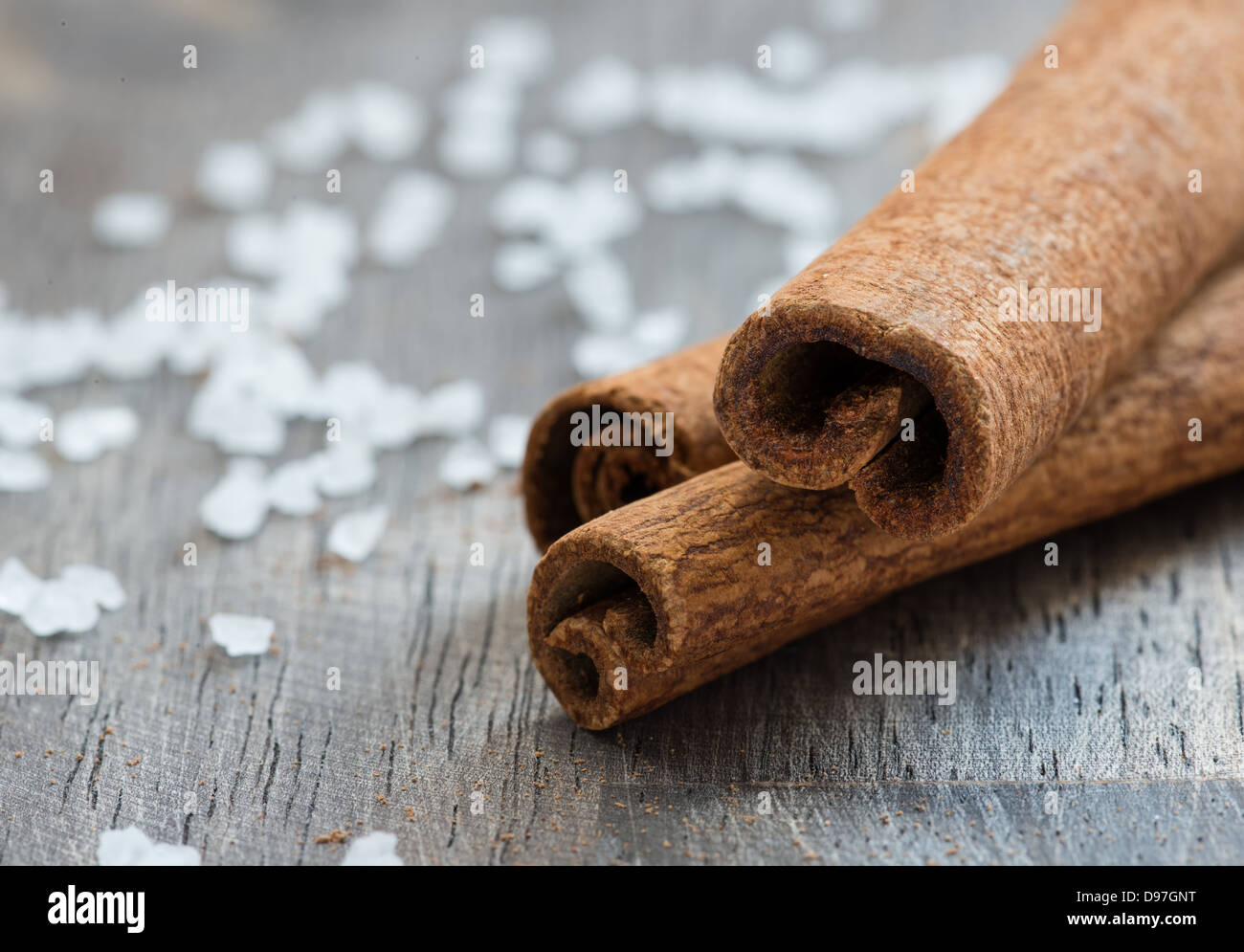 Cinnamon (cassia) sticks and sea salt over wooden background, selective