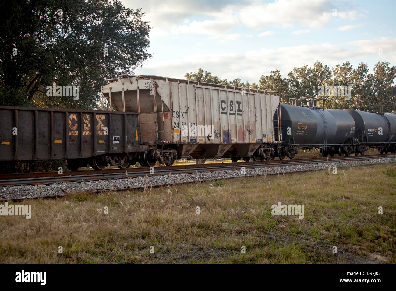 A CSX freight train including tank cars passes through a rural area