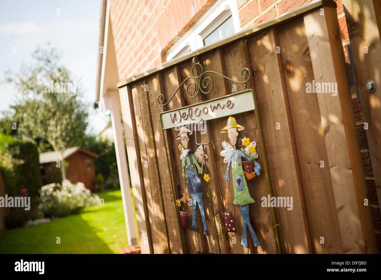 open garden side gate with welcome sign showing the garden with shed in background. Stock Photo