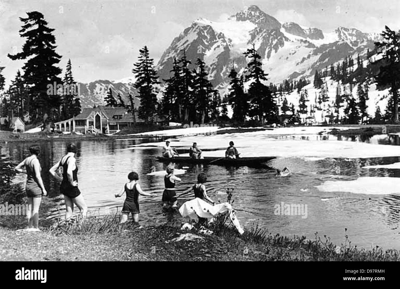 Tourists enjoy swimming and boating at Sunrise Lake, located near Mt. Baker Lodge in Mount Baker National Forest, captured by photographer Bert Huntoon, highlighting the recreational activities in the area. Stock Photo