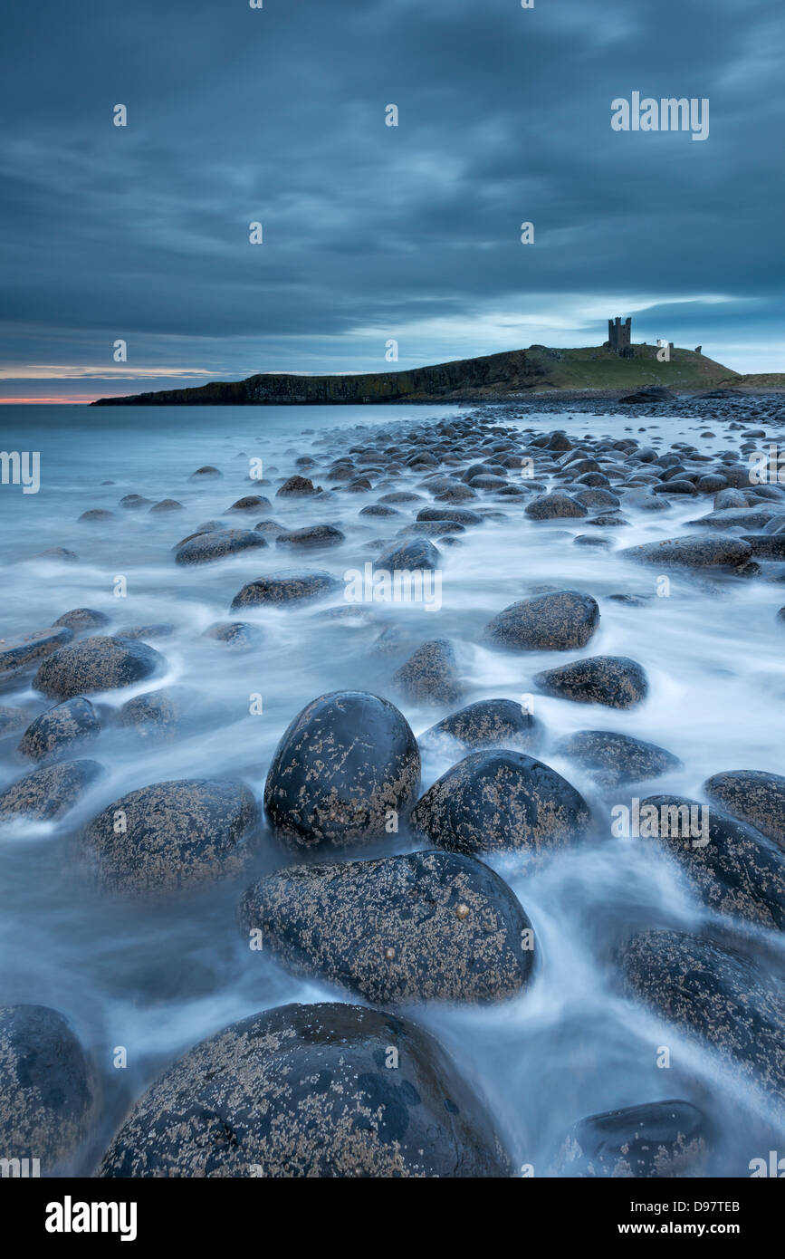 Dunstanburgh Castle at dawn from Embleton Bay, Northumberland, England. Spring (April) 2013. Stock Photo
