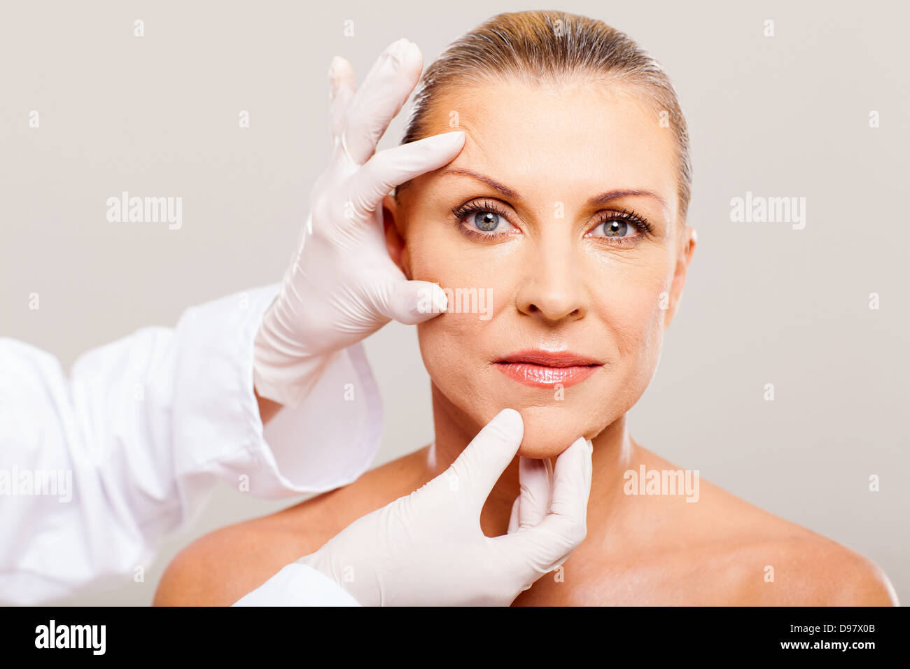 surgeon doing skin check on mid age woman before plastic surgery Stock
