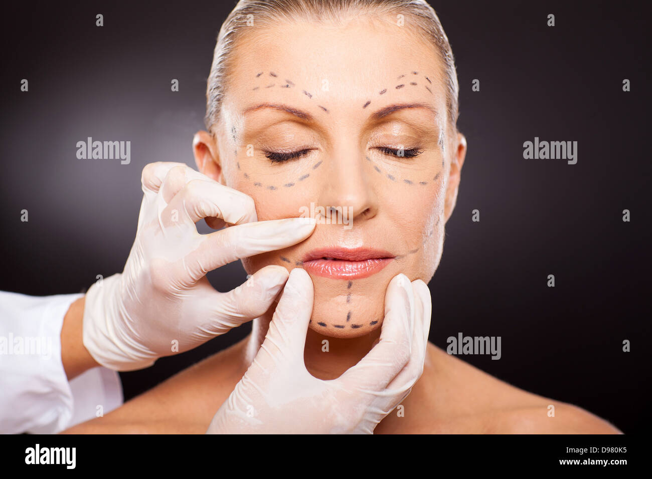 doctor hands on mid age woman before cosmetic surgery Stock Photo