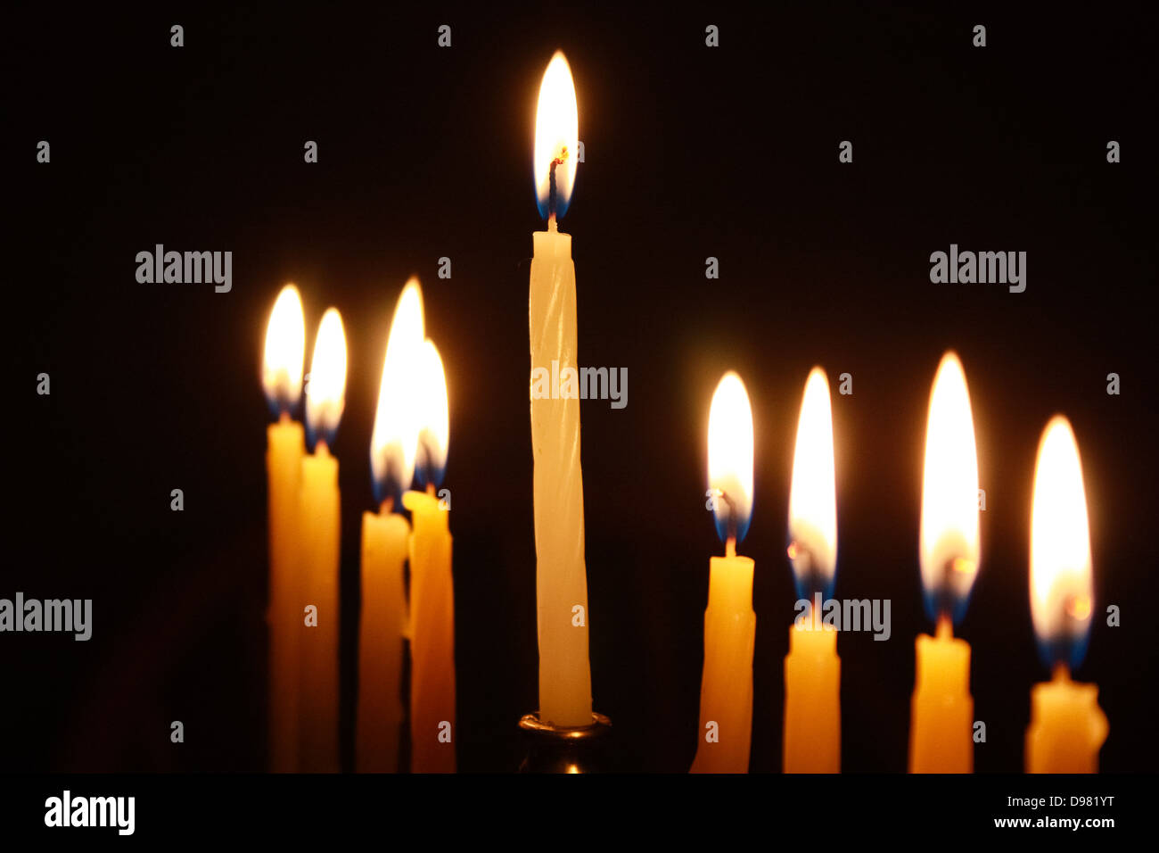 Closeup on candles of lit menorah against black background Stock Photo