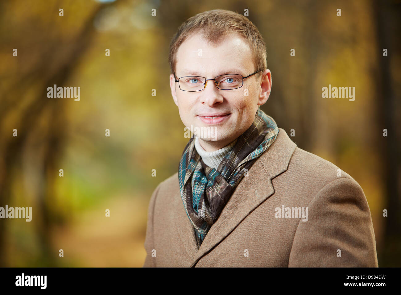 Portrait of elegant young man wearing coat and scarf looking at camera ...