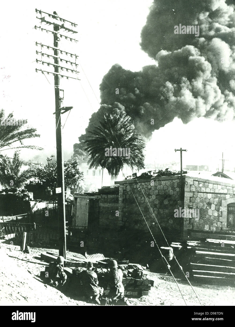 Suez Crisis or Tripartite Agression, 1956. French parachutists in action against Egyptian forces at Port Said. A fuel dump is burning in the background. Stock Photo