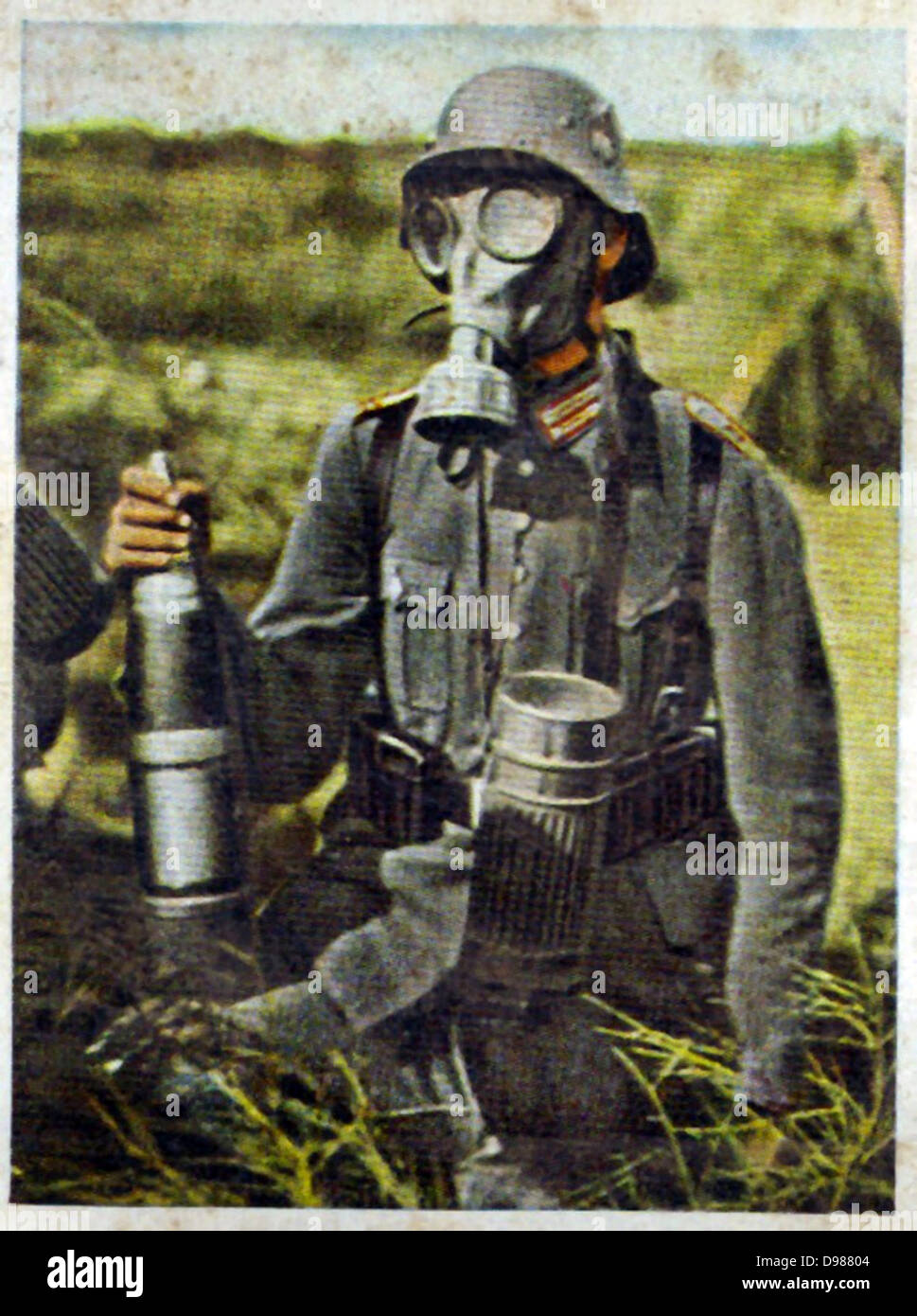 German re-armament and militarisation: Chemical warfare preparation. A gunner, holding a shell, on exercises wearing a gasmask. From series of 270 cigarette cards 'Die Deutsche Wehrmacht', Dresden, 1936. Stock Photo