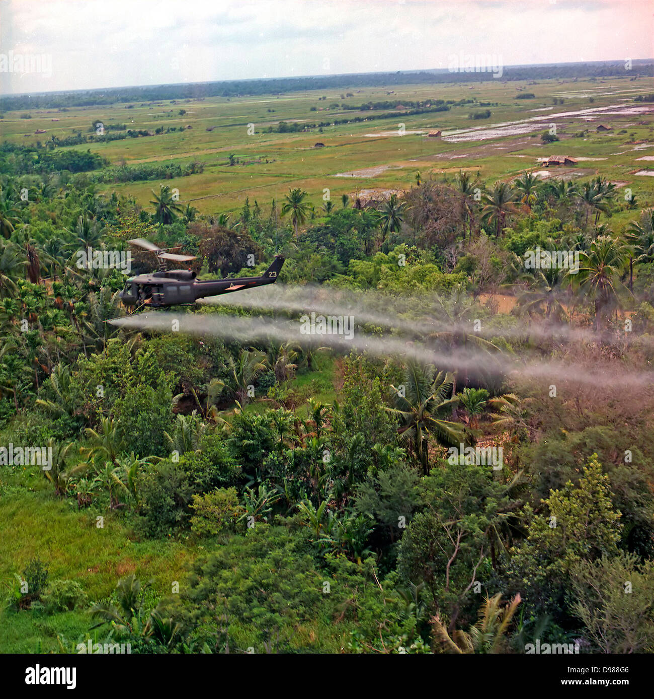 A UH-1D helicopter from the 336th Aviation Company sprays a defoliation agent on a dense jungle area in the Mekong Delta, 26 July 1969. Stock Photo