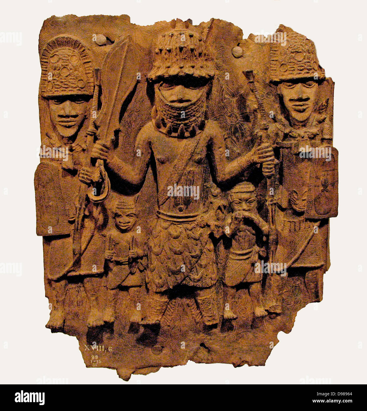 Plaque showing the facade of the royal palace.  Plaques may be seen attached to the pillars that support the palace roof.  They appear to have been made in matching pairs and are shown in such detail that some actual plaques can be readily identified.  Behind the main figures are two brass leopards and the stone axe heads that are kept on altars.  Attached to the roof of the tower is a large brass python. Stock Photo