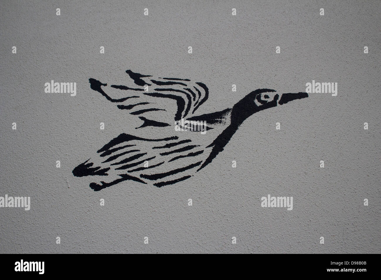 A spray painted graffiti duck, in black on a grey background in the style of Banksy. Stock Photo