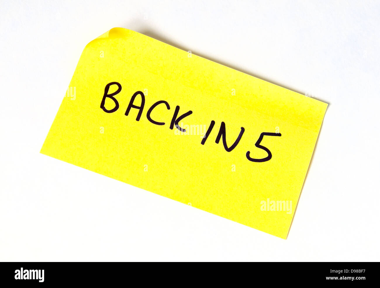 Back in 5 written on a yellow post it note Stock Photo