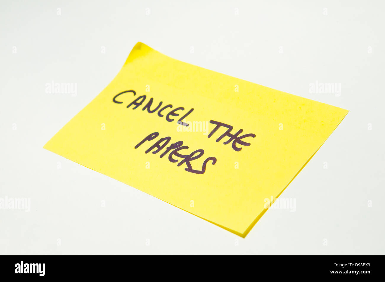 'Cancel the papers' written on a yellow post it note Stock Photo