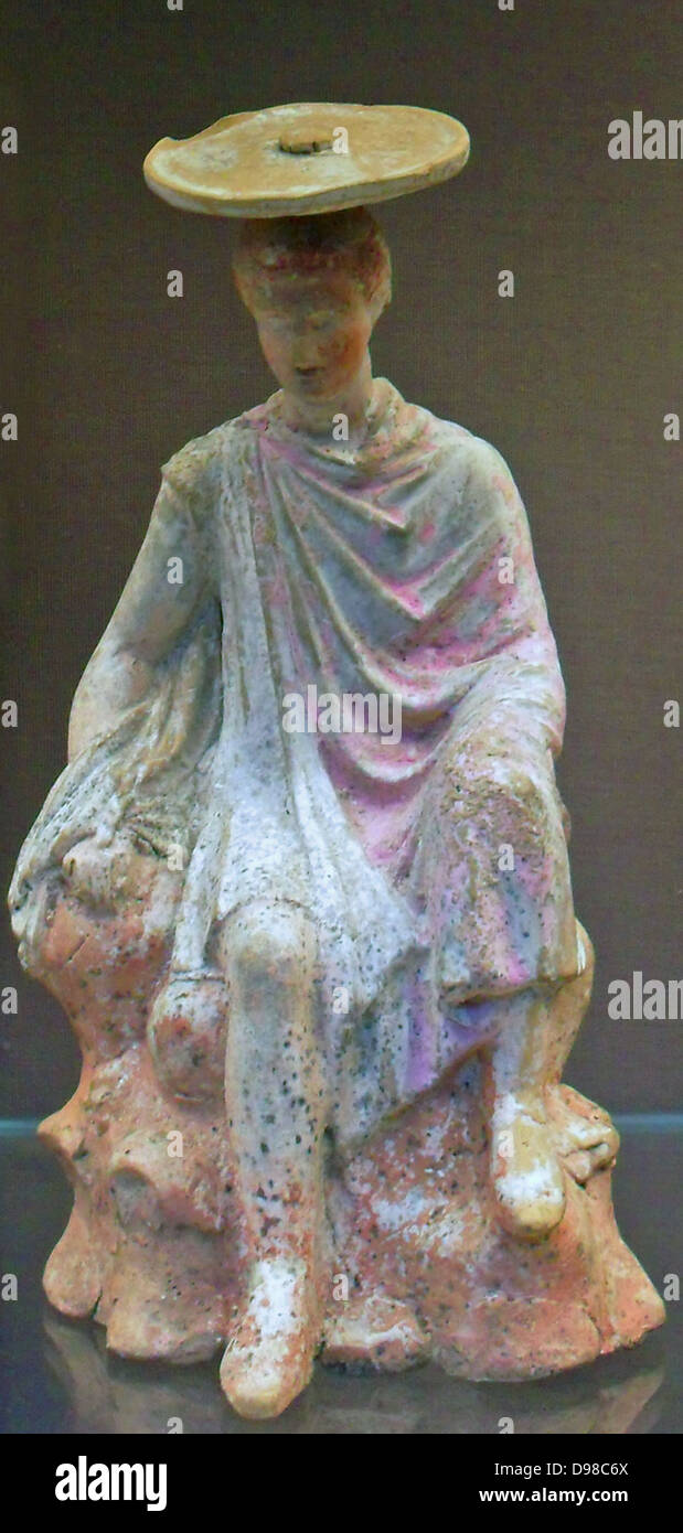 Terracotta figure of a young male sitting on a rock. From Boeotia 300BC. Said to be from Tanagra.   The colours are well preserved. Stock Photo