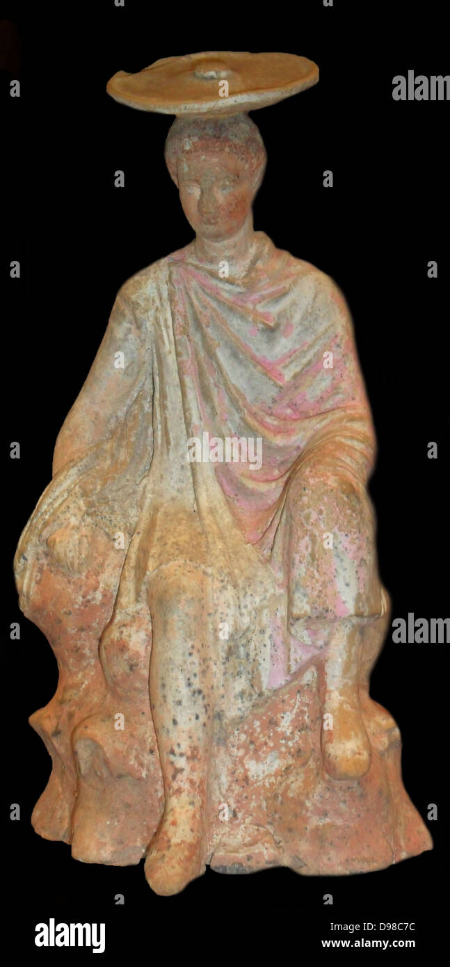 Terracotta figure of a young male sitting on a rock. From Boeotia 300BC. Said to be from Tanagra.   The colours are well preserved. Stock Photo