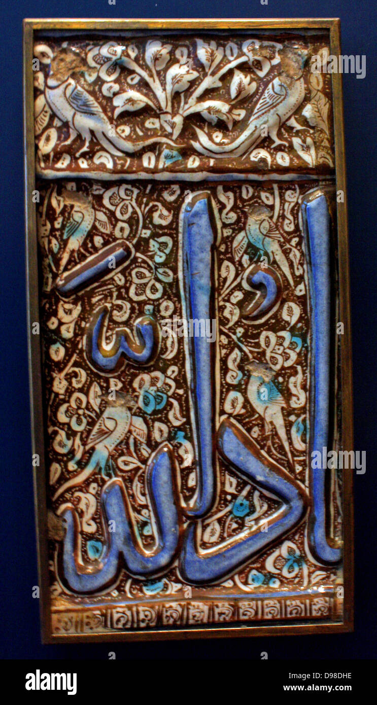 Calligraphy.  Square tile with holy names, Iran, 1400-1500.  Fritware, with decoration in coloured glazes.  It is inscribed with the names of Allah, the prophet Muhammad and his son-in-law and successor Ali in square Kufic script. Calligraphy panel, possibly from a cenotaph, Iran 1400-1500.  Wood with carved decoration. Stock Photo