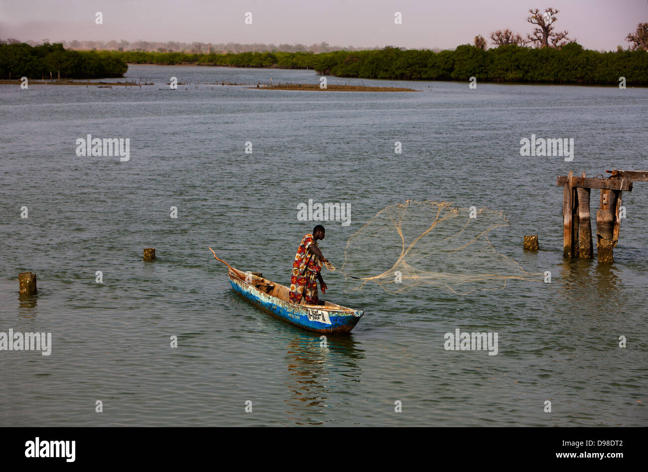 Senegal Africa West Africa Fadiouth Island fisherman casting net with canoe (Pirogue) Stock Photo