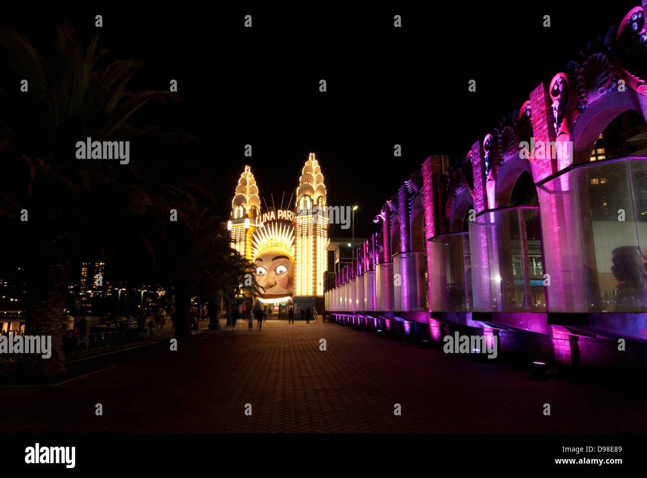 The face of Luna Park at night, with the lights outside Sydney Olympic Swimming Pool on the right. Stock Photo