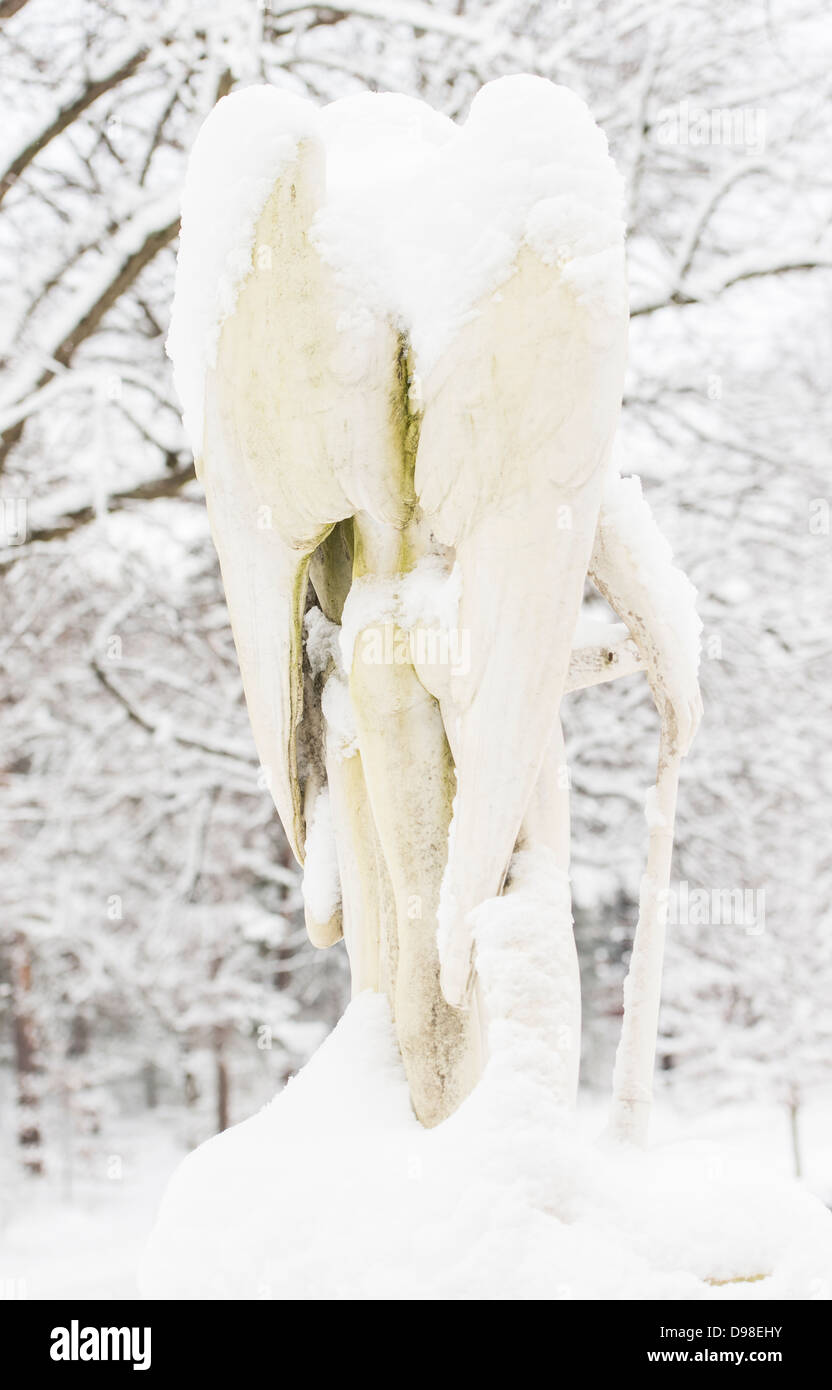 Backside of sculpture of white angel covered in snow. Cemetery in Stockholm, Sweden. Stock Photo