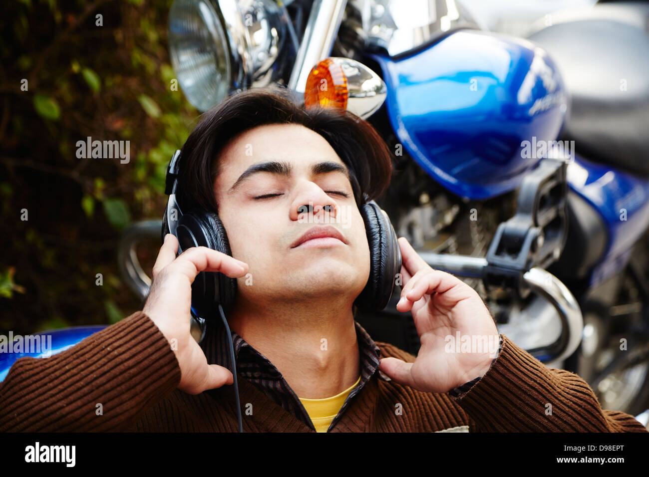 Man listening to music with headphones next to motorcycle Stock Photo -  Alamy