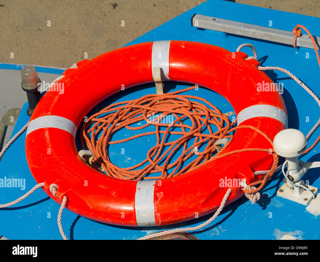 Colourful orange lifebelt and rope on a small boat. Stock Photo