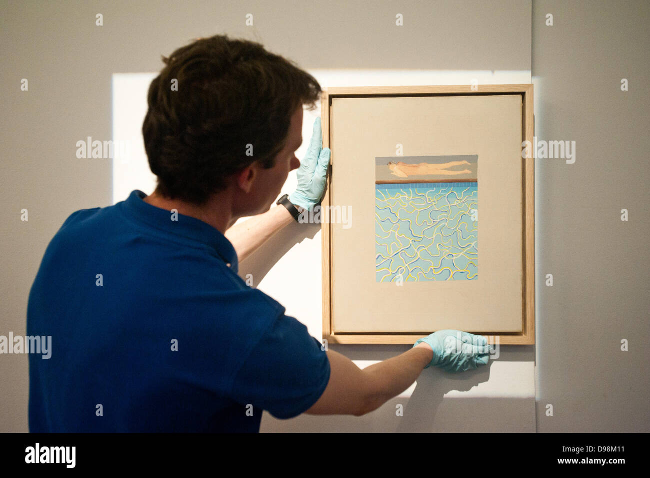 London,UK - 14 June 2013: A Sotheby's employee hangs David Hockney’s 1967 Californian Pool painting during the preview of this summer auction at Sotheby's. Credit:  Piero Cruciatti/Alamy Live News Stock Photo
