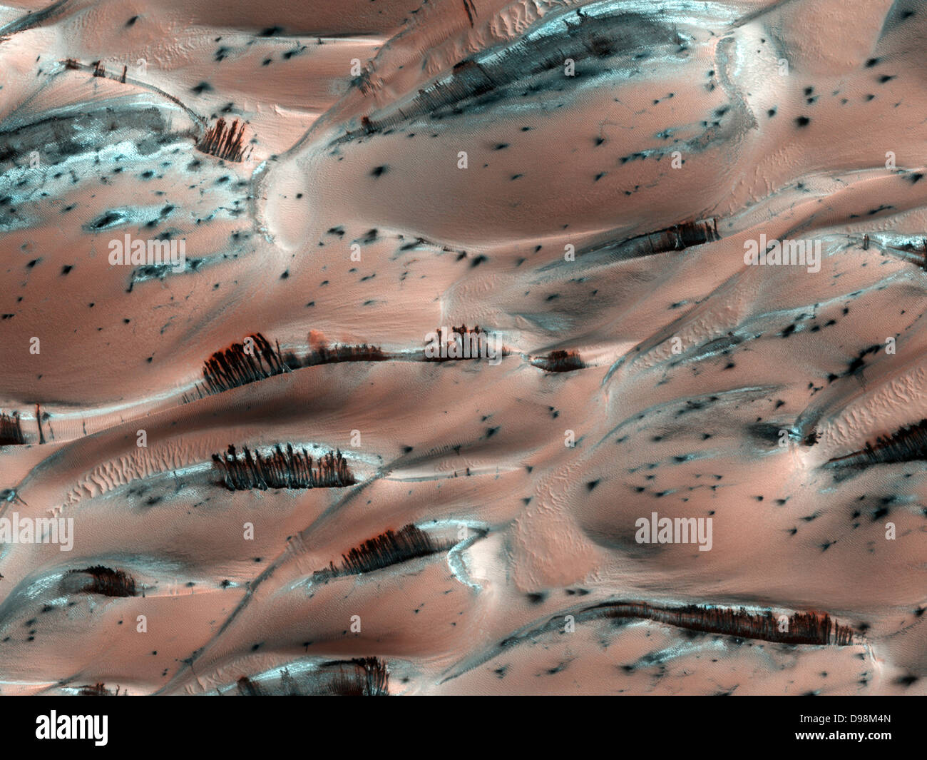 dark streaks of sediment on the downwind side of the dunes on the surface of Mars. They were created by escaping gas from the evaporating carbon dioxide ice below. The bottom of the ice melts into vapour and moves toward holes in the ice, carrying dark sediment along with it that is then deposited when the gas escapes. This image was taken by the High Resolution Imaging Science Experiment (HiRISE) camera on NASA’s Mars Reconnaissance Orbiter in April 2008. Stock Photo