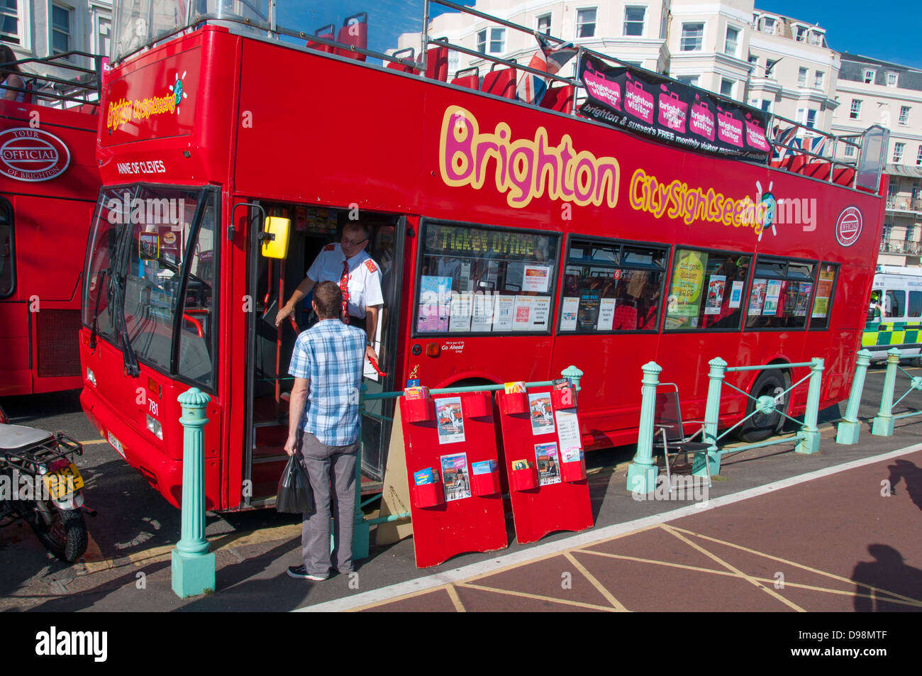 A man talking to the driver of a stationary Brighton, open top, sightseeing bus alongside the promenade, on a warm day in early autumn. England, UK. Stock Photo