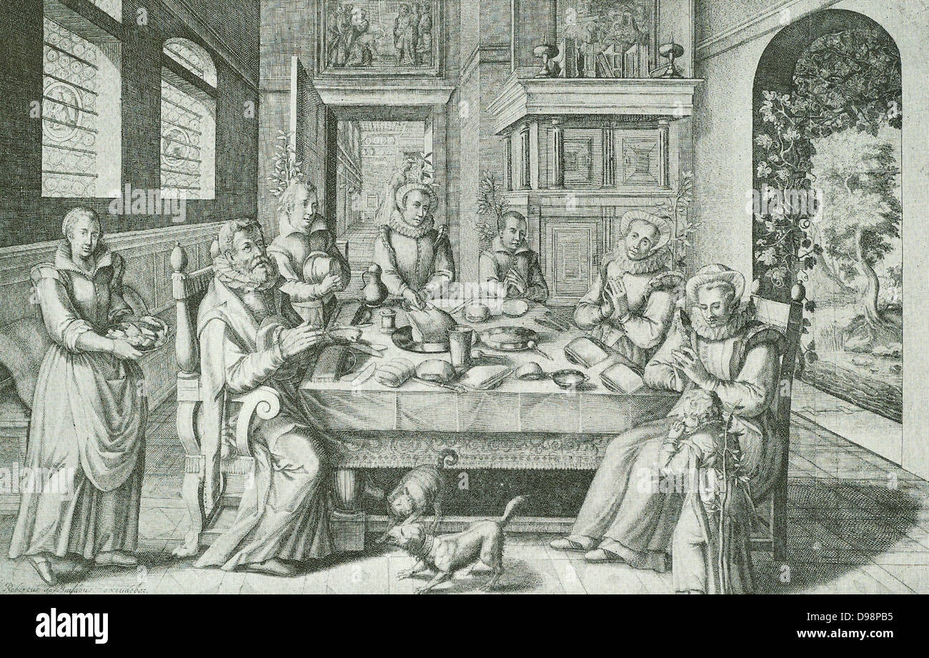 A well-to-do Dutch family (seventeenth century) round the large dinner-table at prayer.  The meaning of the vine and the olive-branches is - thy wife shall be as a fruitful vine by the sides of thine house, thy children like olive plants around about thy table. Stock Photo