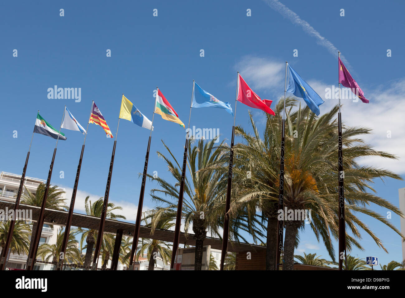 Flags of regions of Spain on flagpoles against blue sky Stock Photo